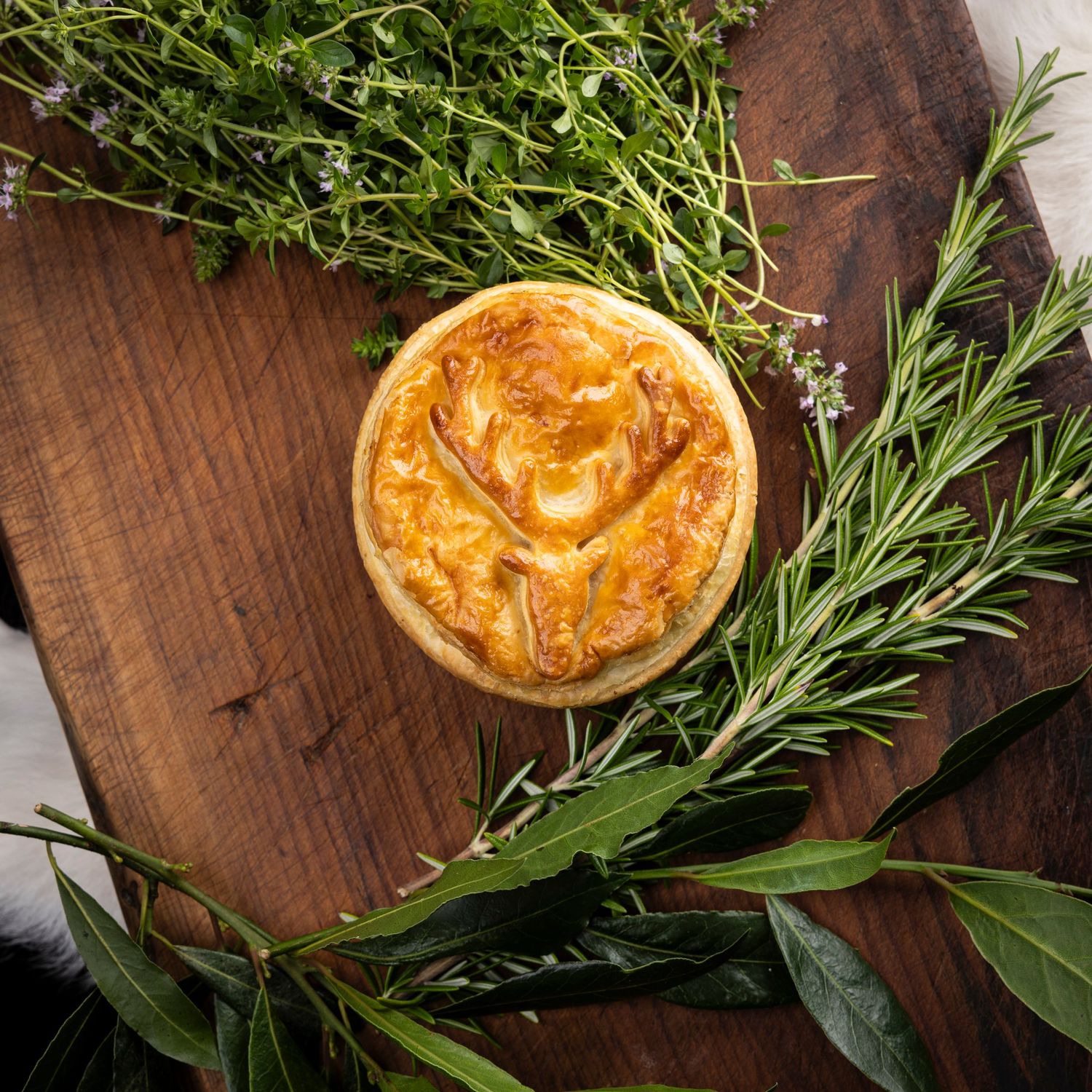 Fresh herbs and golden baked pastry arranged on dark wooden surface for food styling.