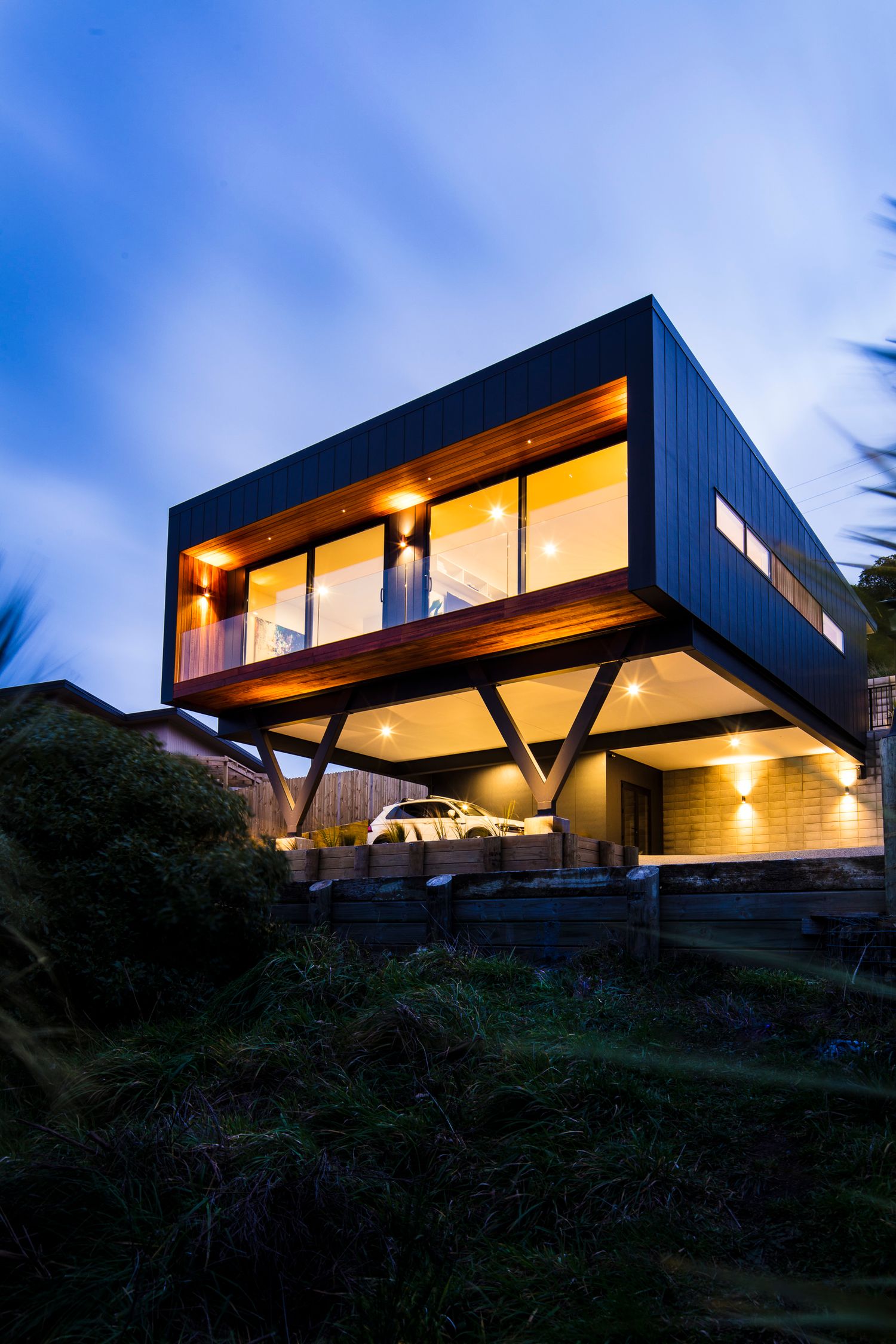 Cantilevered modern house illuminated at night perched on hillside with dramatic architectural design.