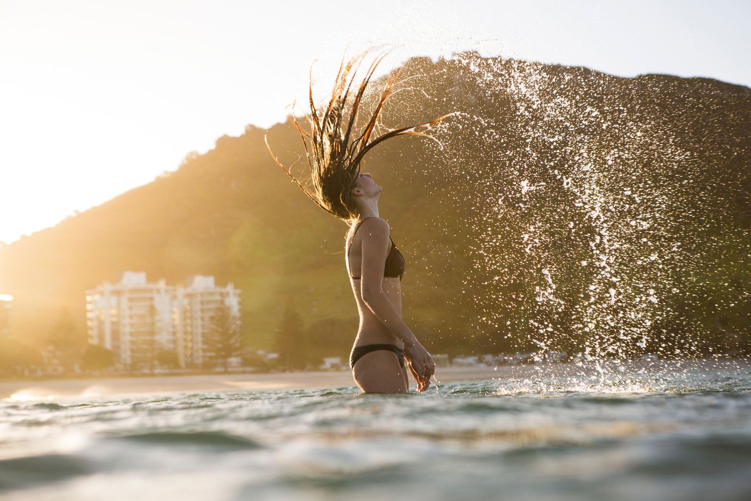 Crystal clear waves break against rocky coastline during golden hour.