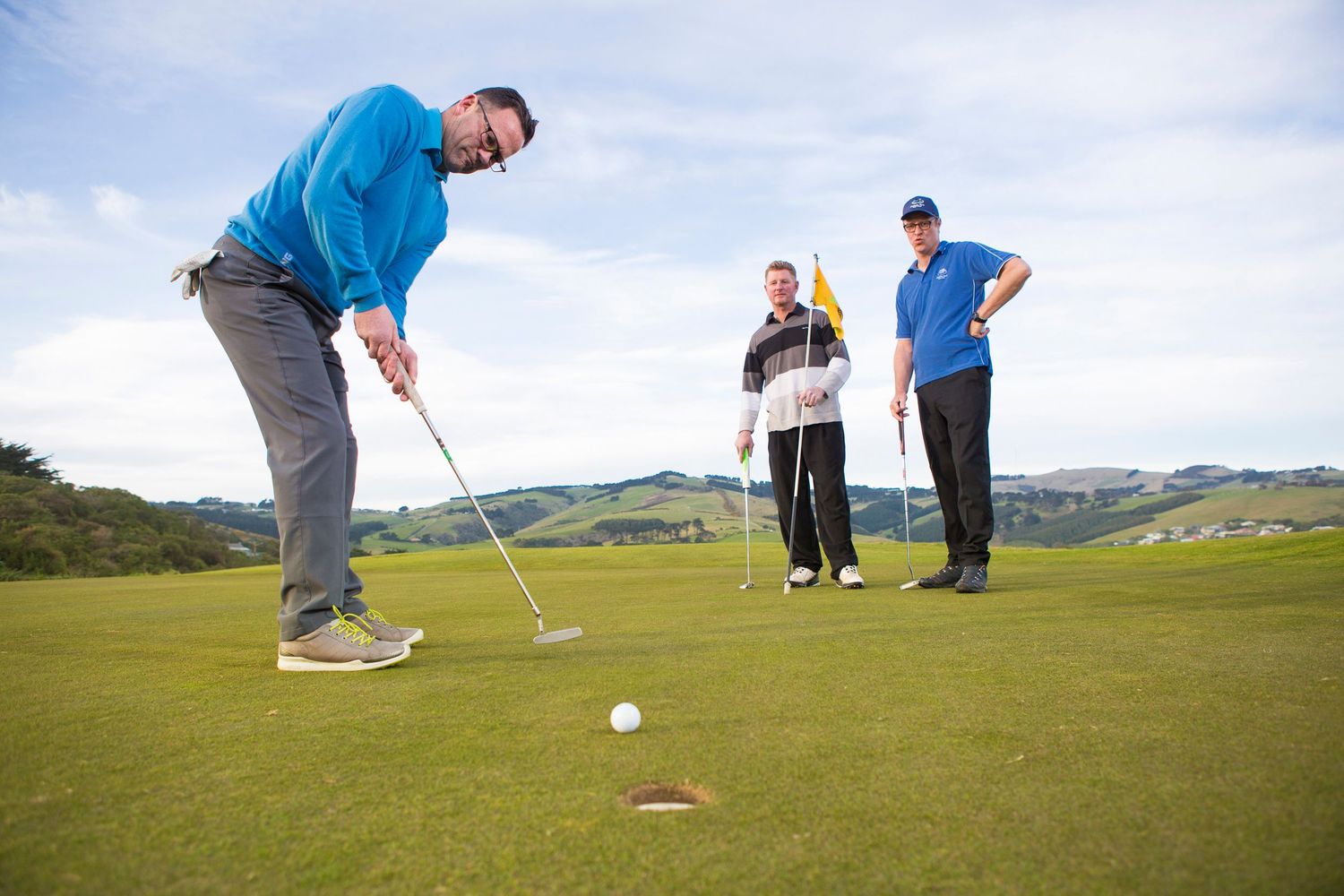 Golfers practicing their putting on a scenic coastal golf course.
