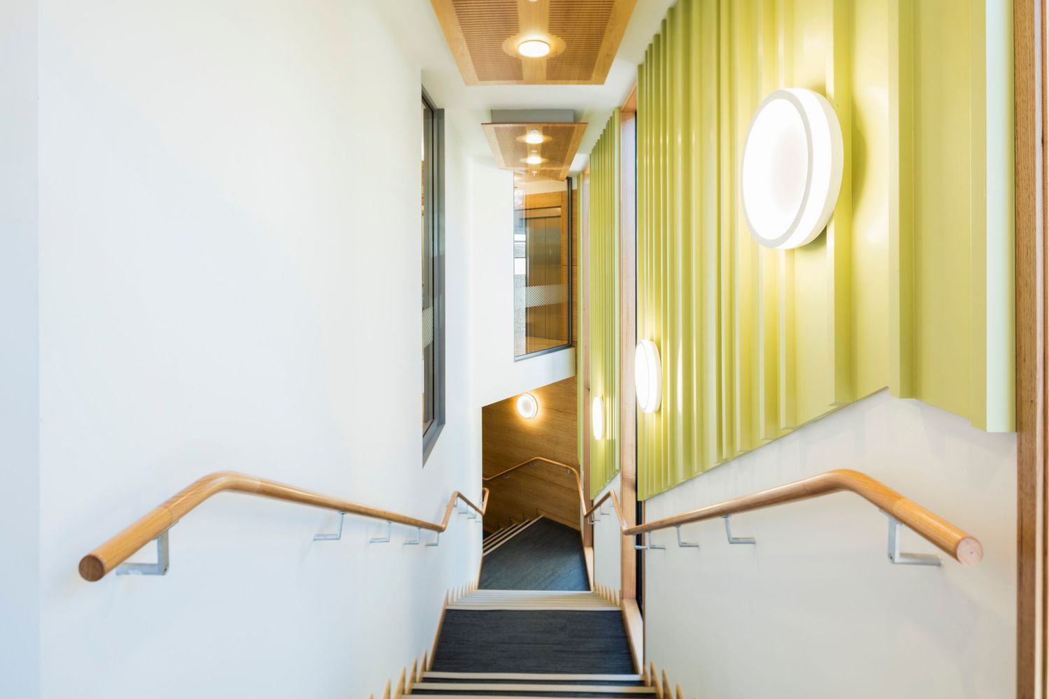 Long corridor with wooden ceiling, yellow walls and modern light fixtures.