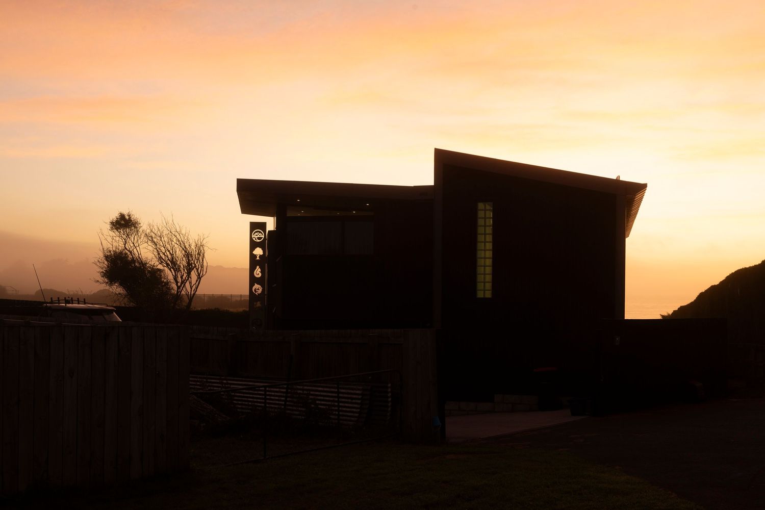 Silhouette of a modern architectural house against a vibrant sunset sky.