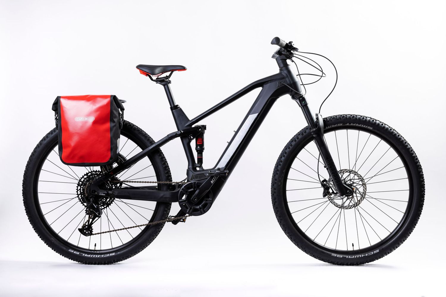 Black electric mountain bike with red saddle bag mounted on white background.