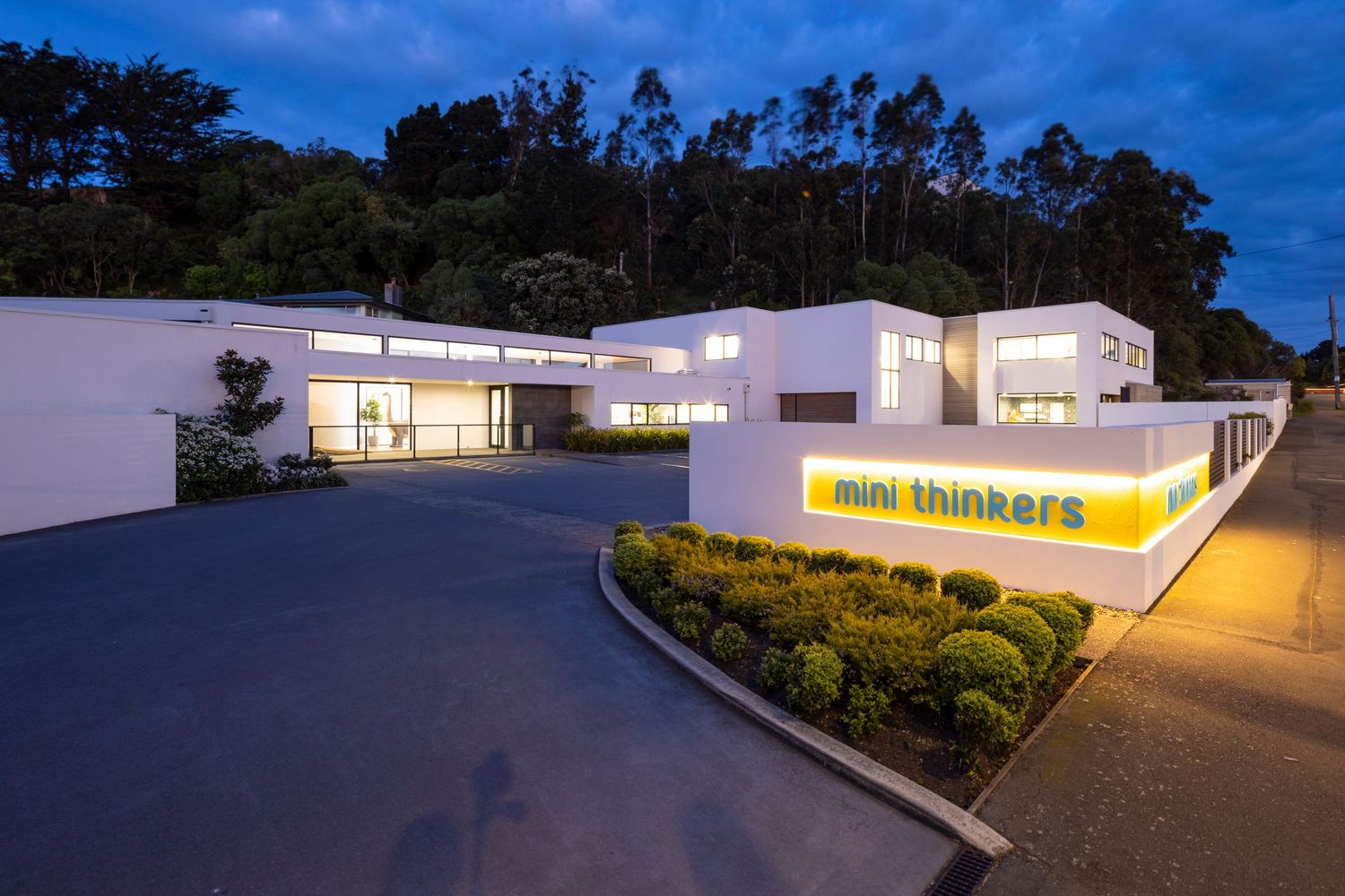 Mini Thinkers building complex illuminated at night with landscaped entrance.