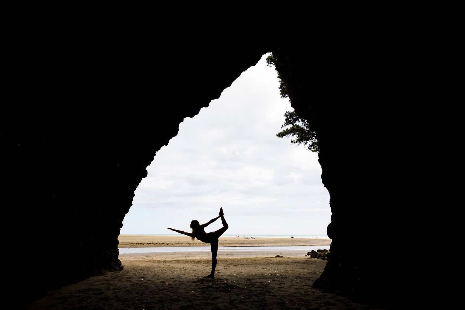 Yoga silhouettes practicing poses against bright coastal background.