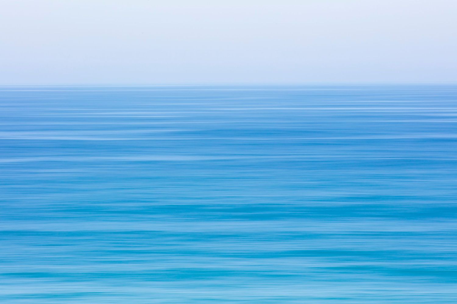 Serene blue ocean surface with gentle ripples creating a minimalist seascape pattern.