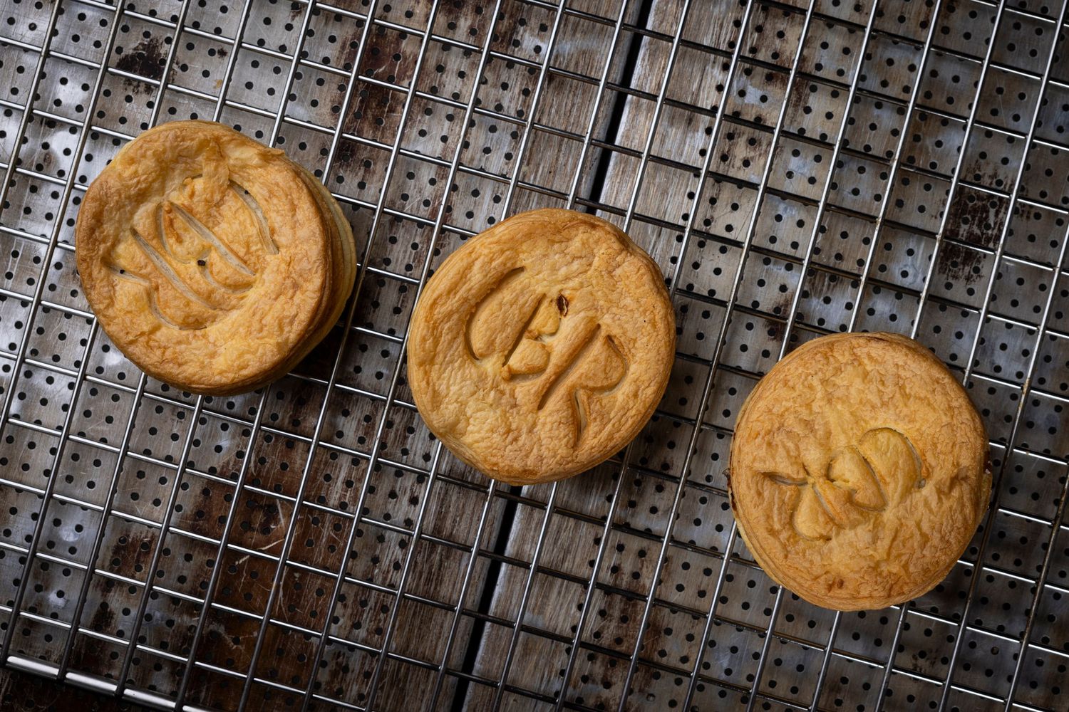 Freshly baked golden cookies cooling on a wire rack against dark background.