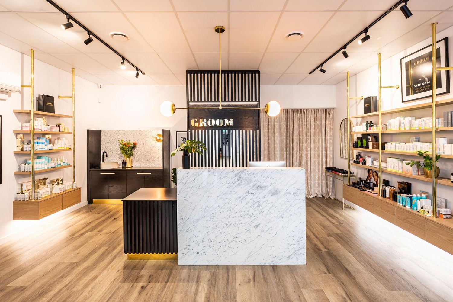 Modern salon reception area with marble counter, track lighting and hardwood floors.