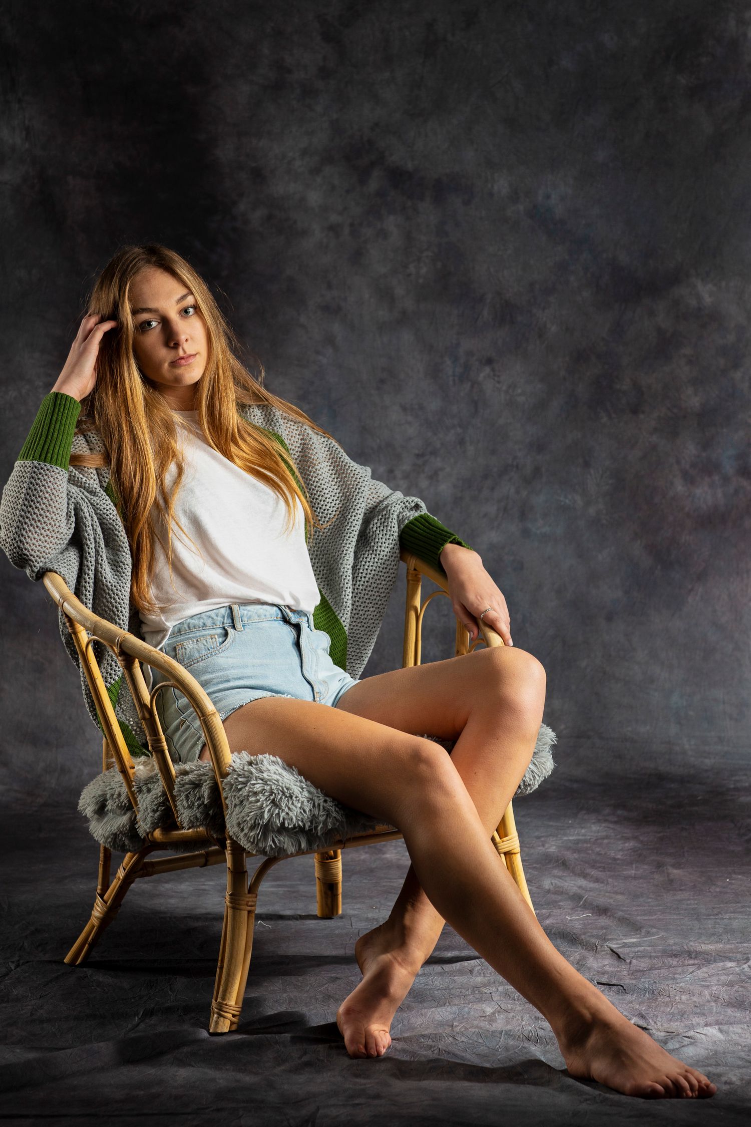 Casual lifestyle portrait of someone relaxing in oversized sweater on rattan chair.
