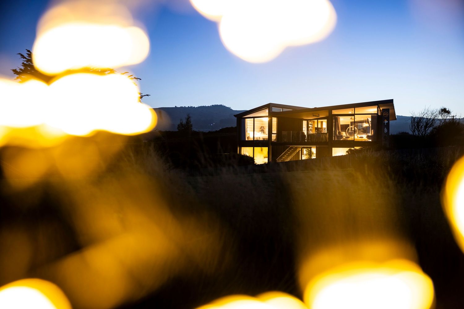 Illuminated building silhouette at dusk with artistic bokeh light effects.