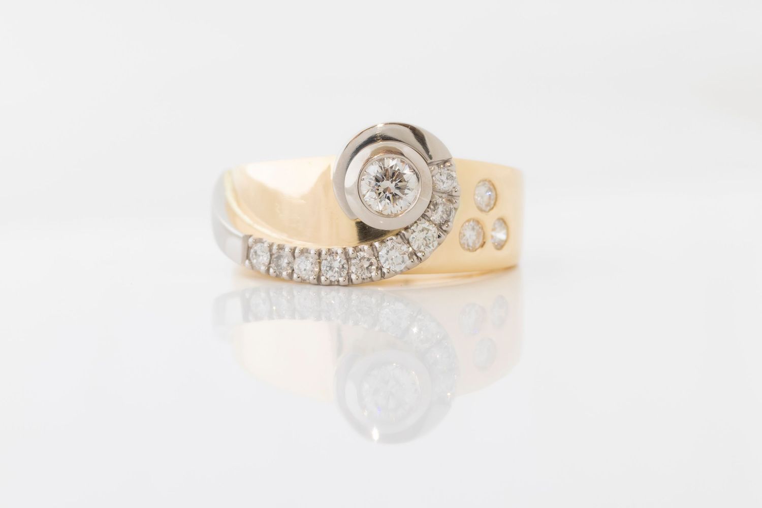 Gold ring with diamonds and a central bezel setting photographed on white background.