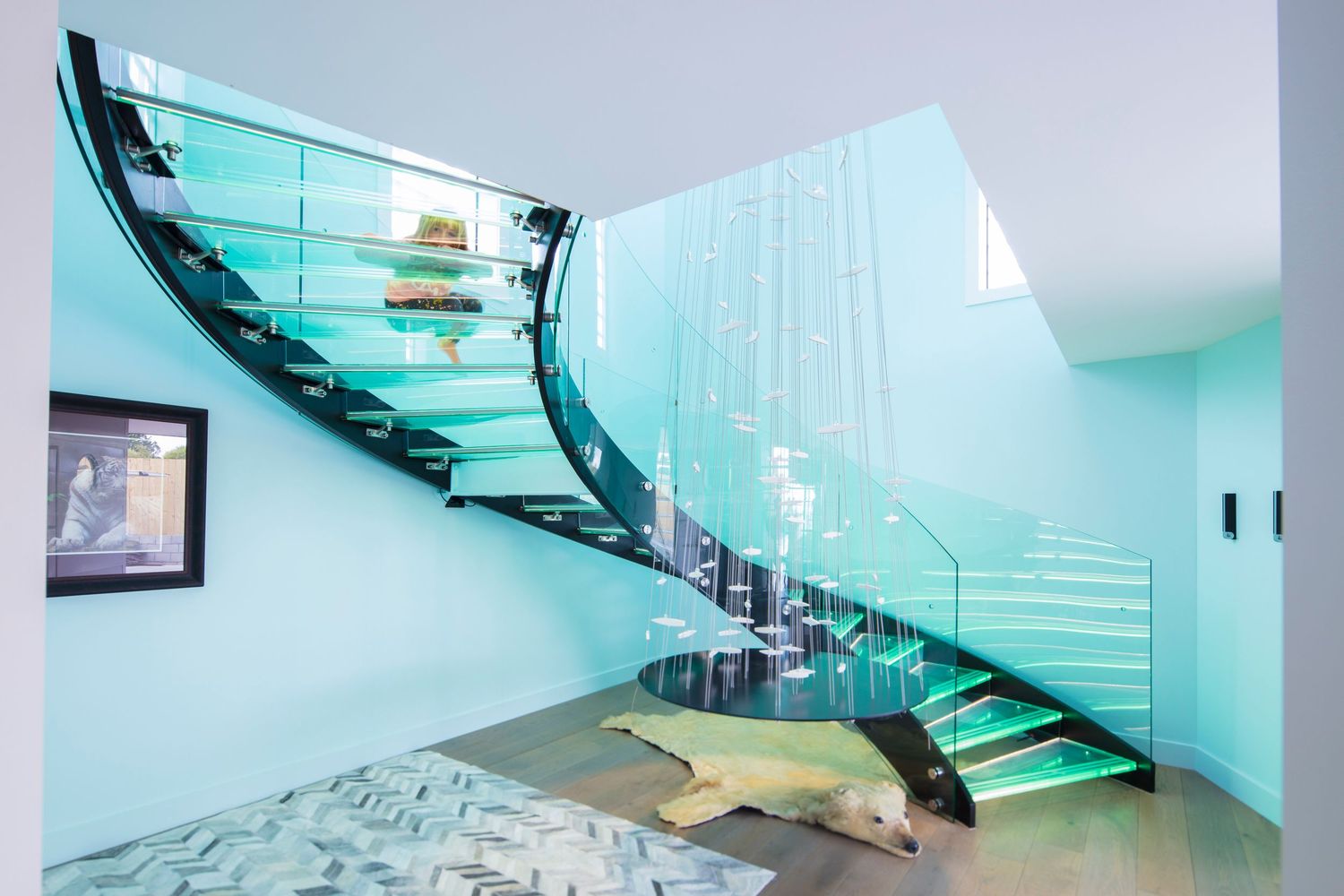 Contemporary glass staircase with turquoise LED lighting and minimalist design.