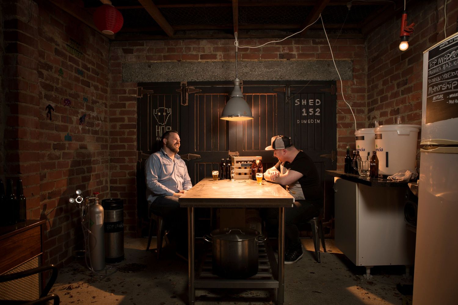 Two people having a meeting at wooden table in rustic brick room with dim lighting.