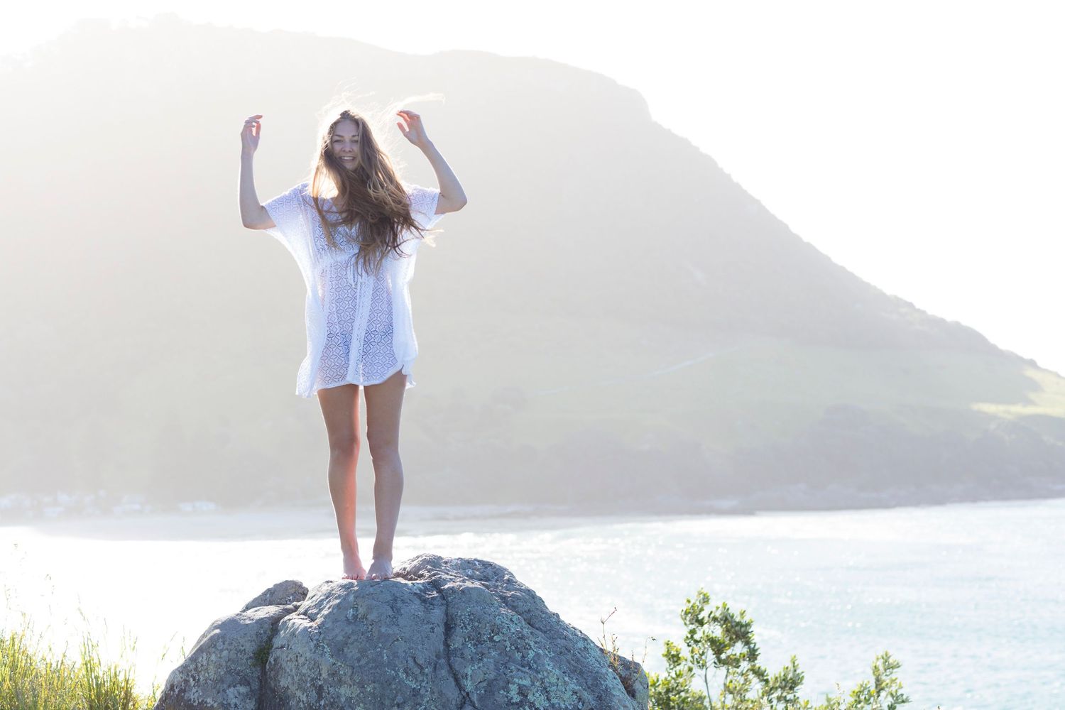 Scenic coastal photography featuring figure poses against mountain and ocean landscape.