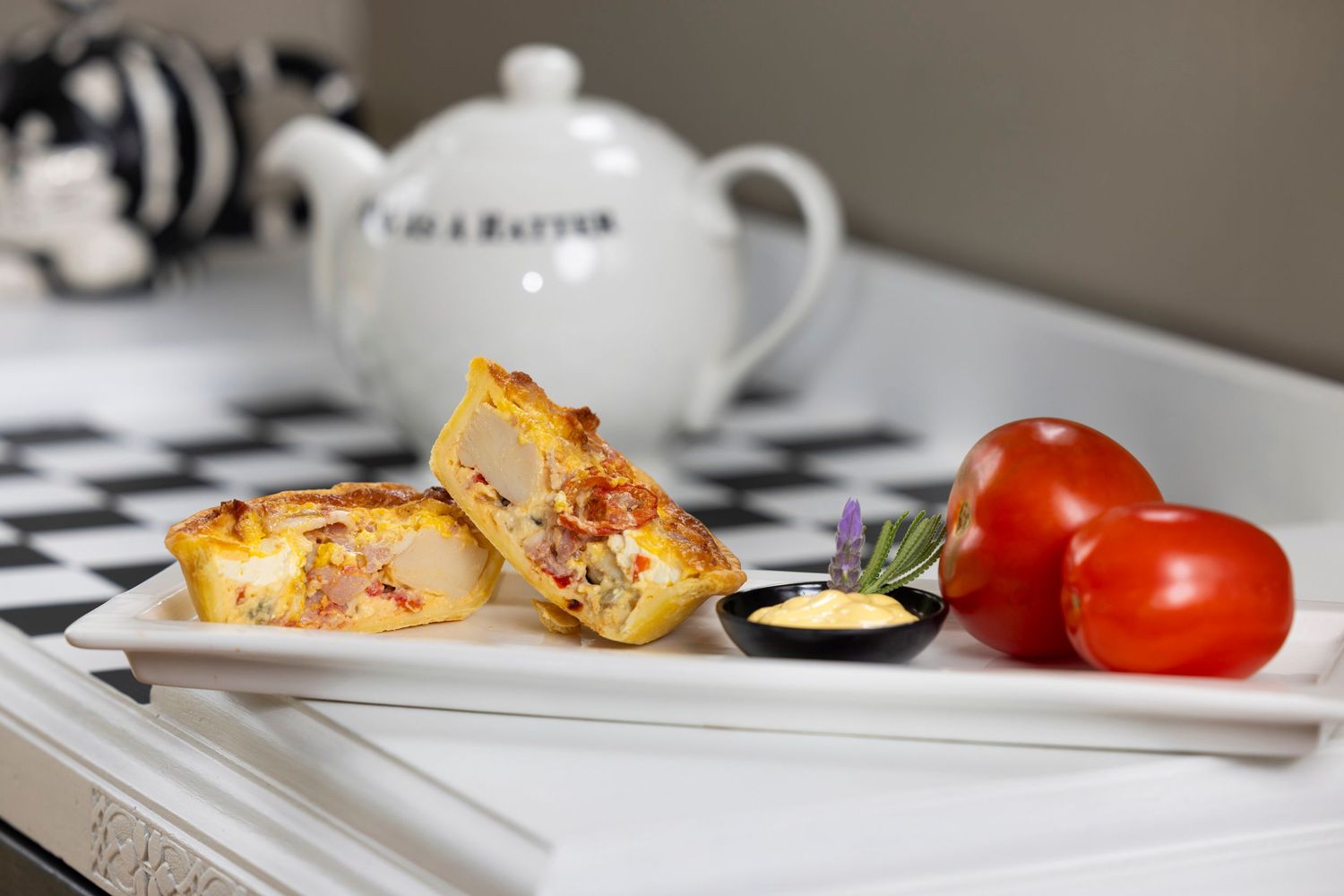 Grilled sandwich with tomatoes and dipping sauce served on white ceramic plate.
