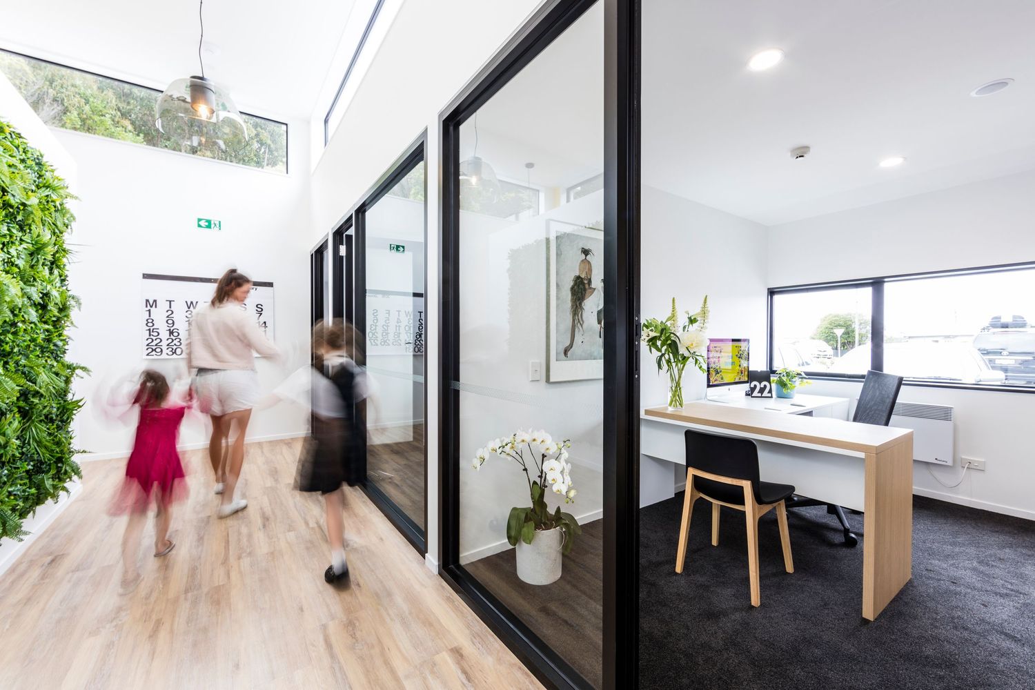 Contemporary office interior with glass walls, wooden floors, and minimalist design elements.