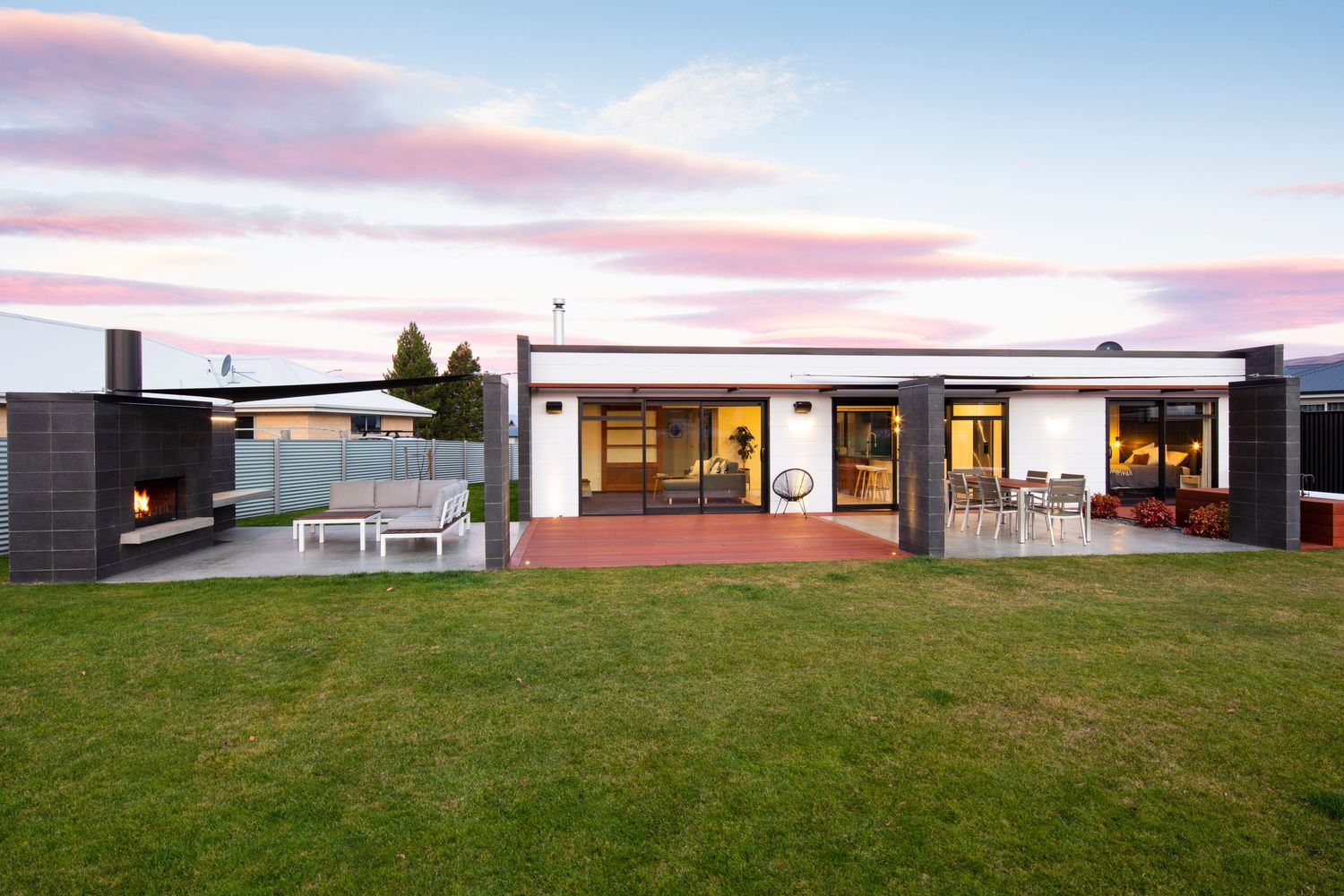 Contemporary rural property with expansive lawn and mountain views at sunset.