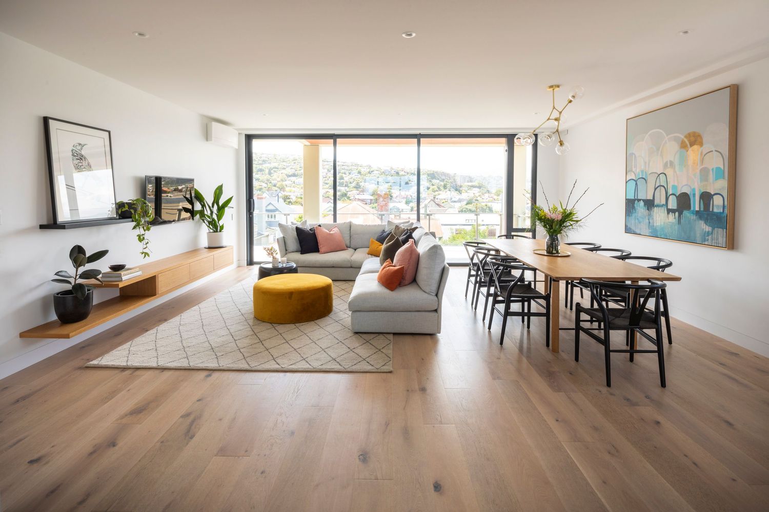 Contemporary open concept living room with hardwood floors and large windows.