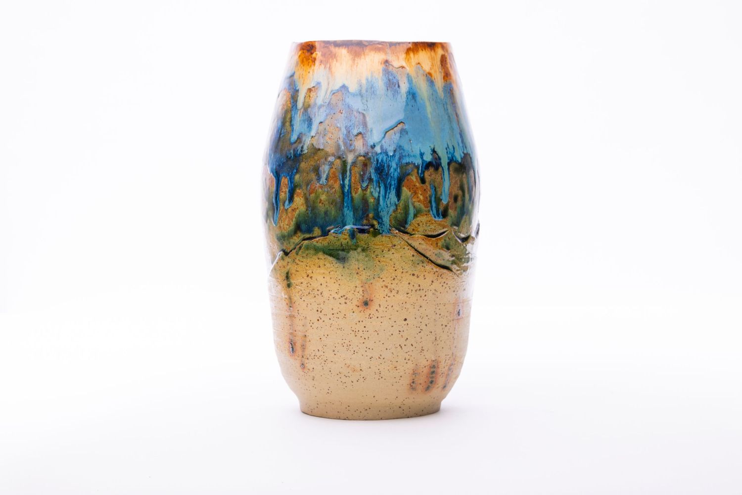 Decorative ceramic vase with blue and orange glazed landscape design on beige background.