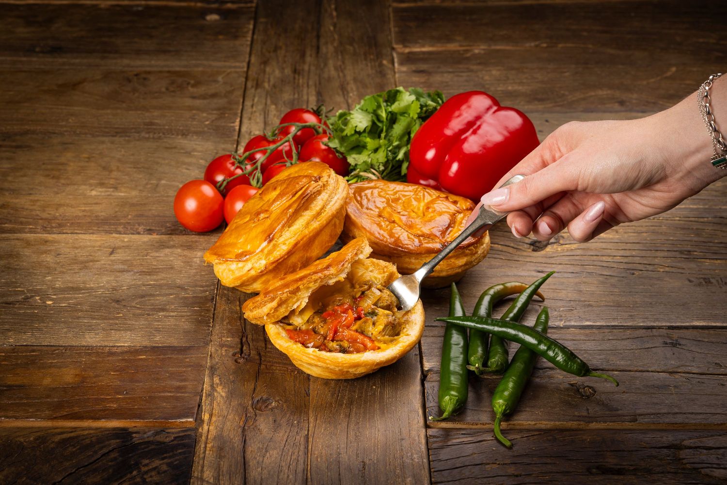 Burger with melted cheese and fresh vegetables displayed on rustic wooden table.