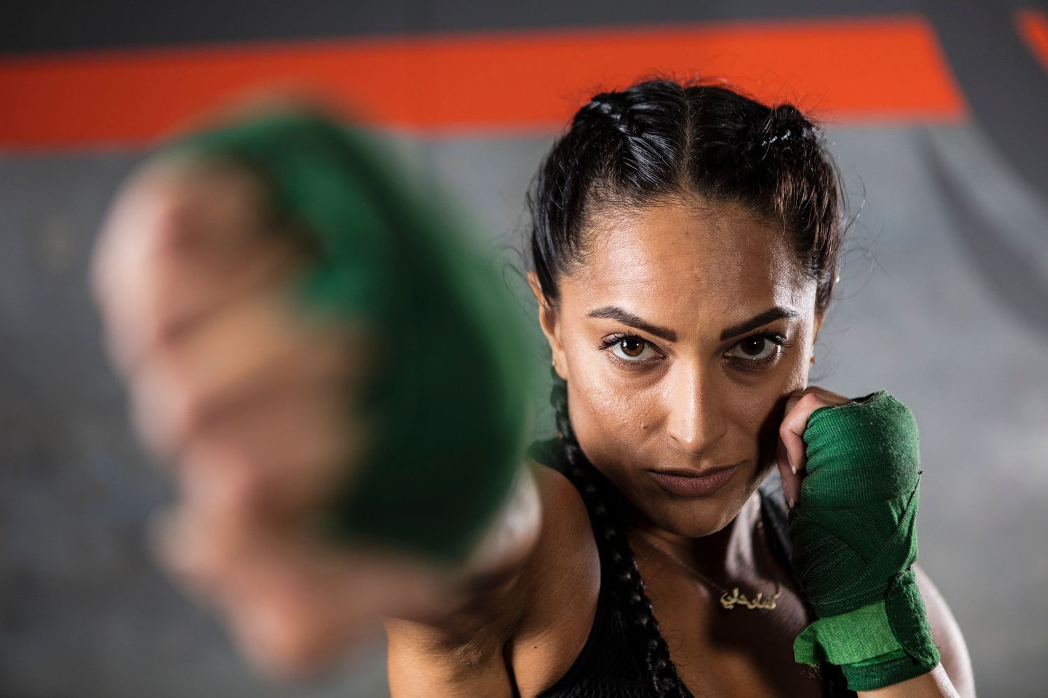 Close up shot of someone wearing green boxing gloves in fighting stance.
