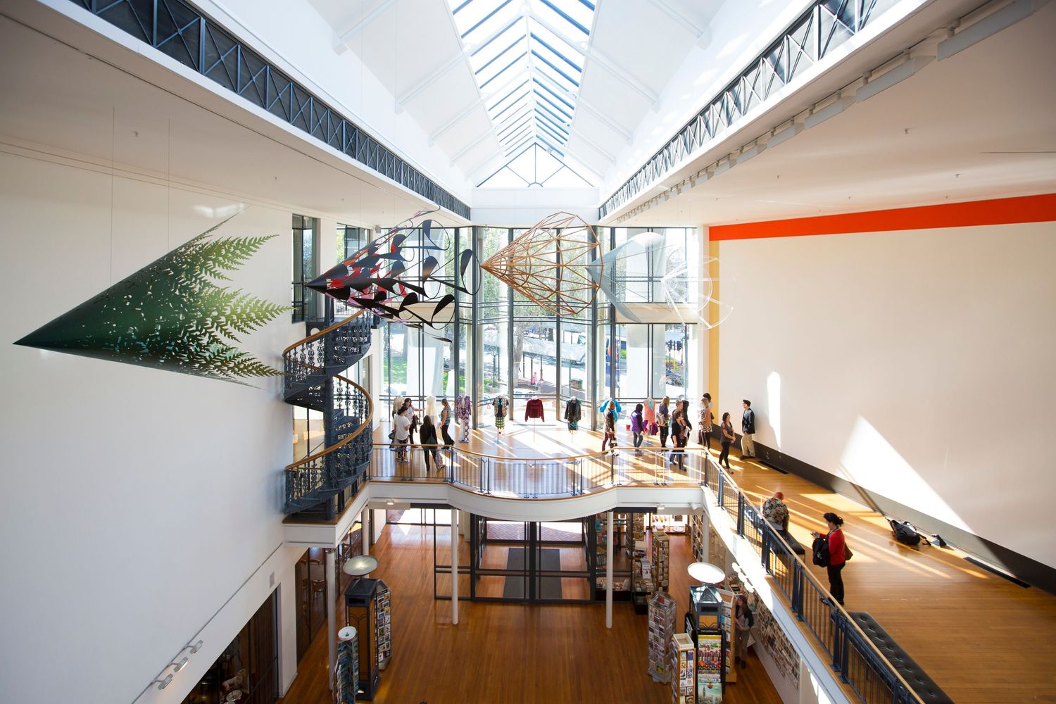 Modern atrium with glass ceiling, multiple levels, and metal staircases in white interior space.