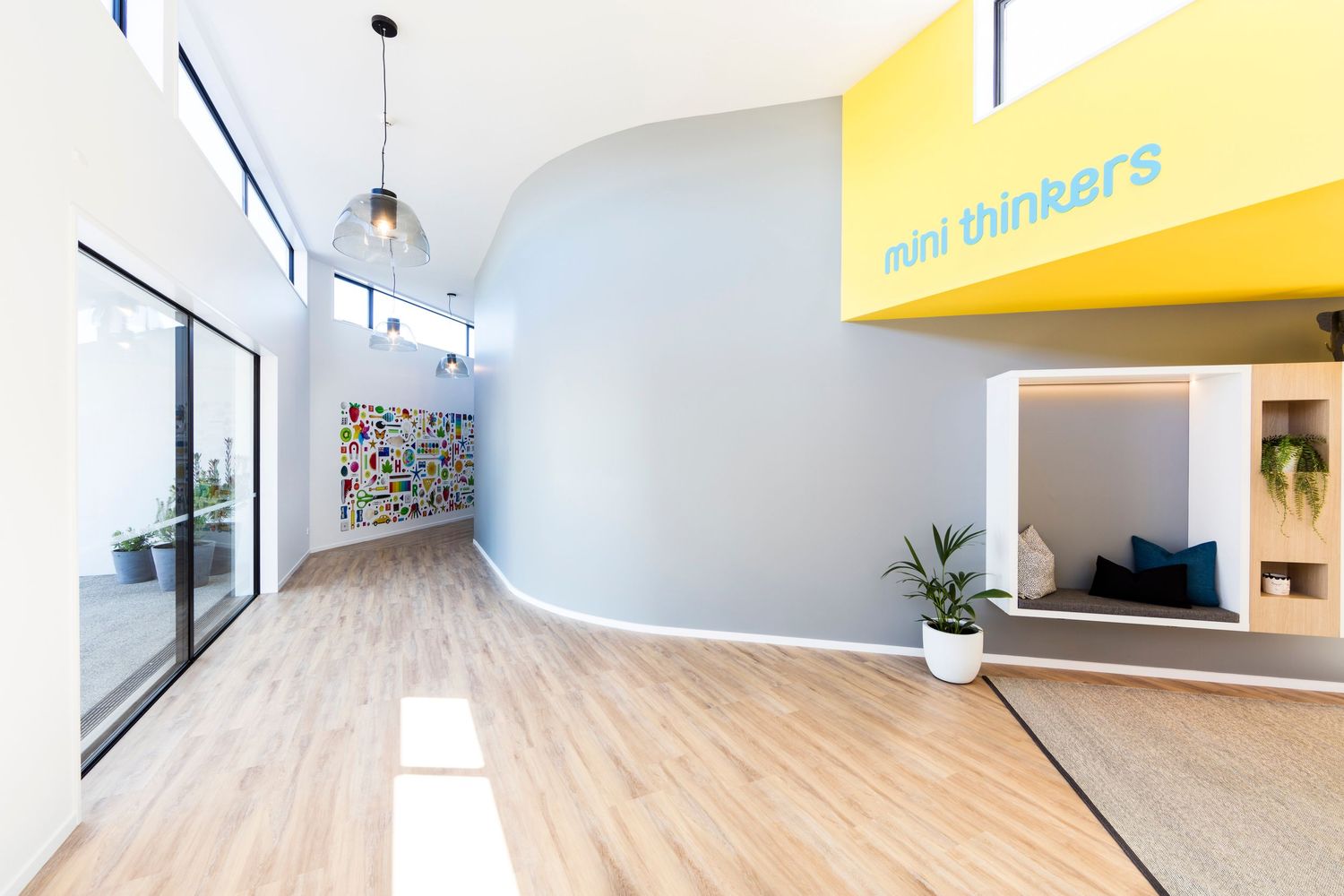 Bright curved hallway with wooden floors and yellow signage.