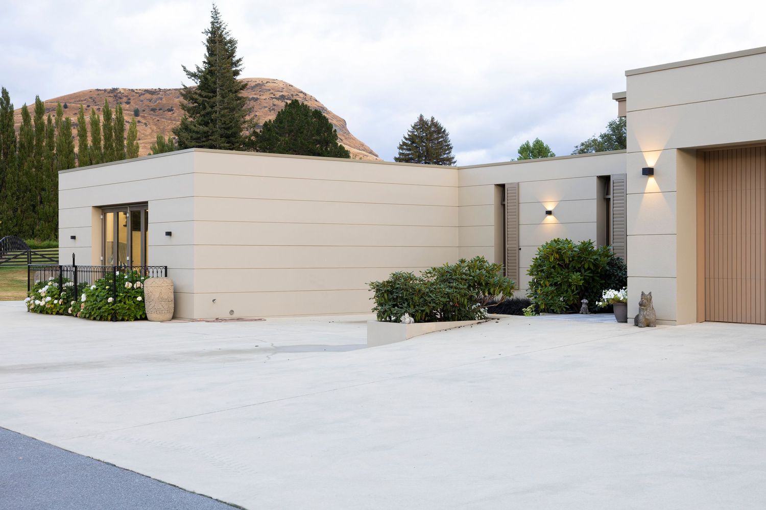 Modern beige commercial building exterior with landscaped entrance and mountain backdrop.