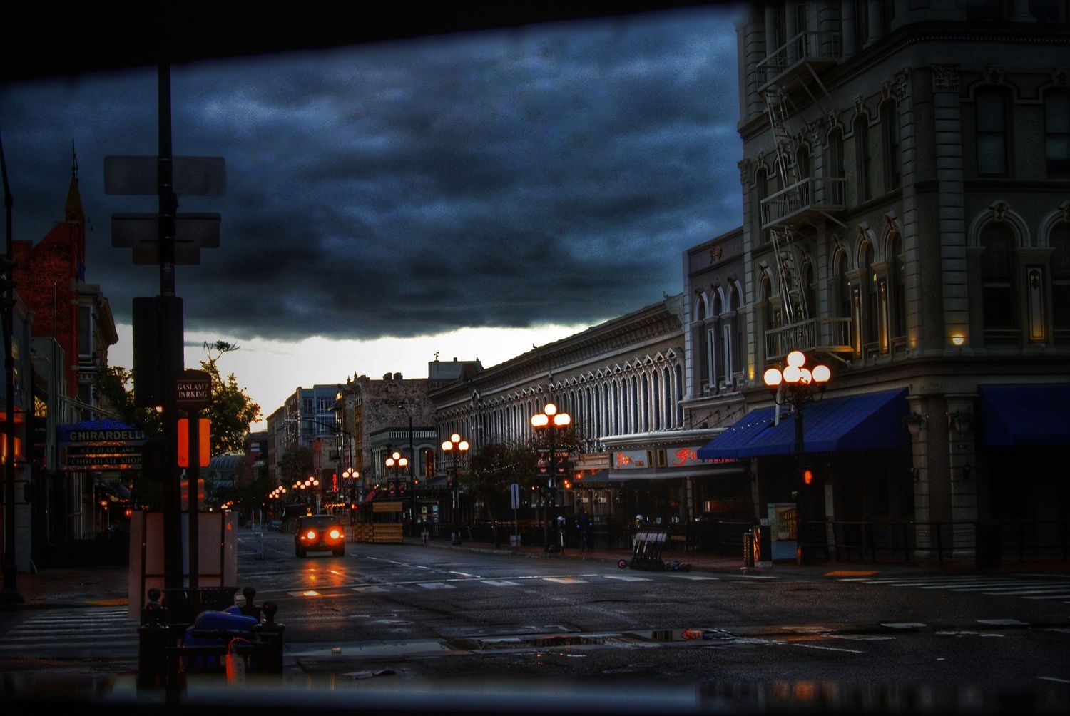 Rainy evening cityscape of historic downtown street with moody storm clouds overhead.