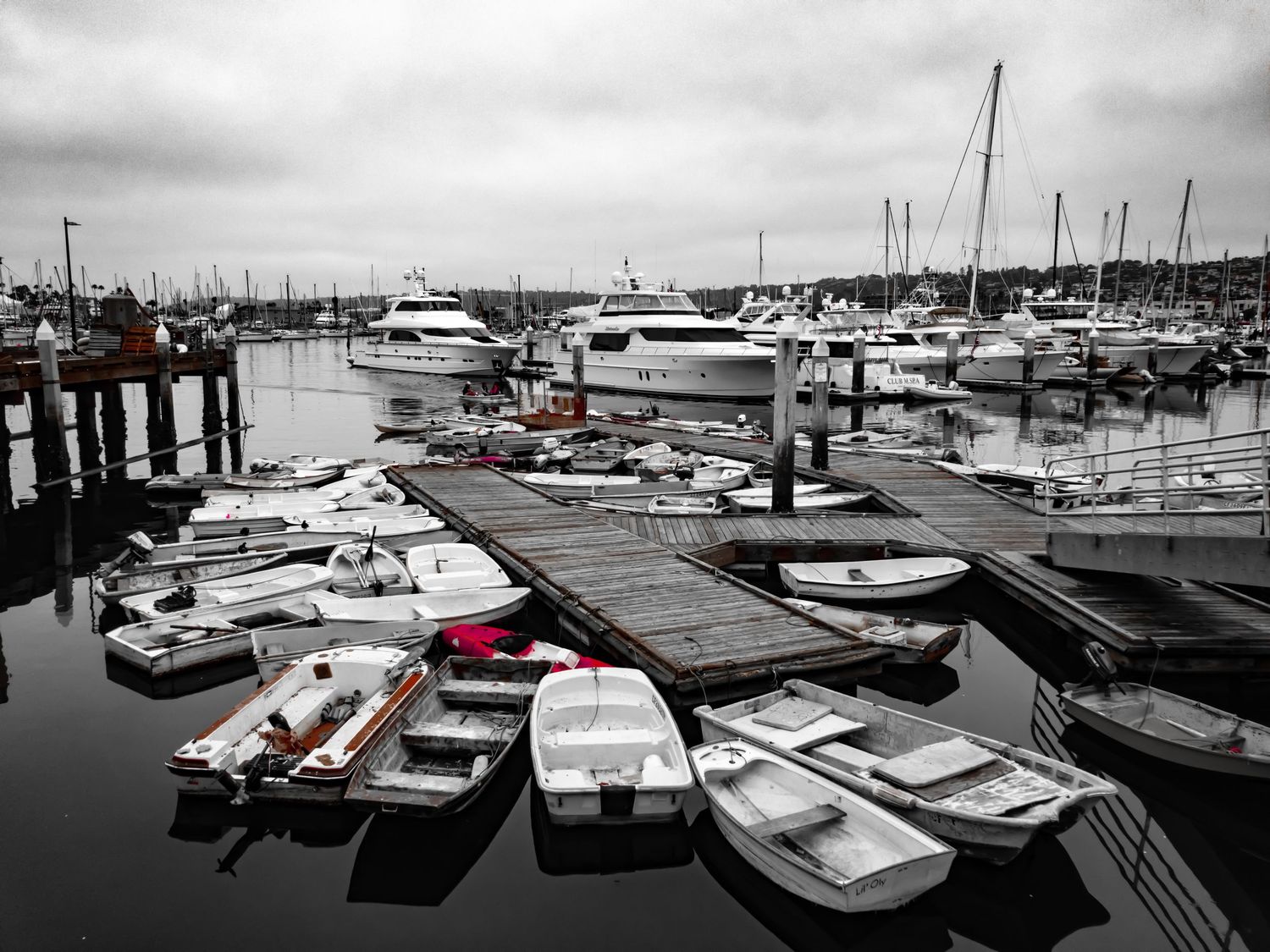 Marina with boats in selective color showing red against black and white background.