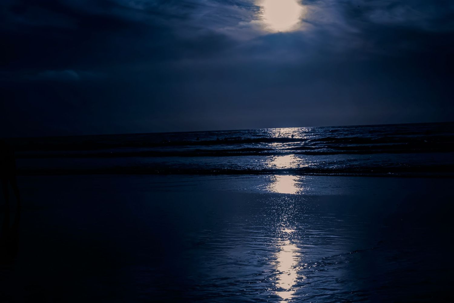 Full moon reflects brilliantly on dark water creating a serene nighttime seascape.