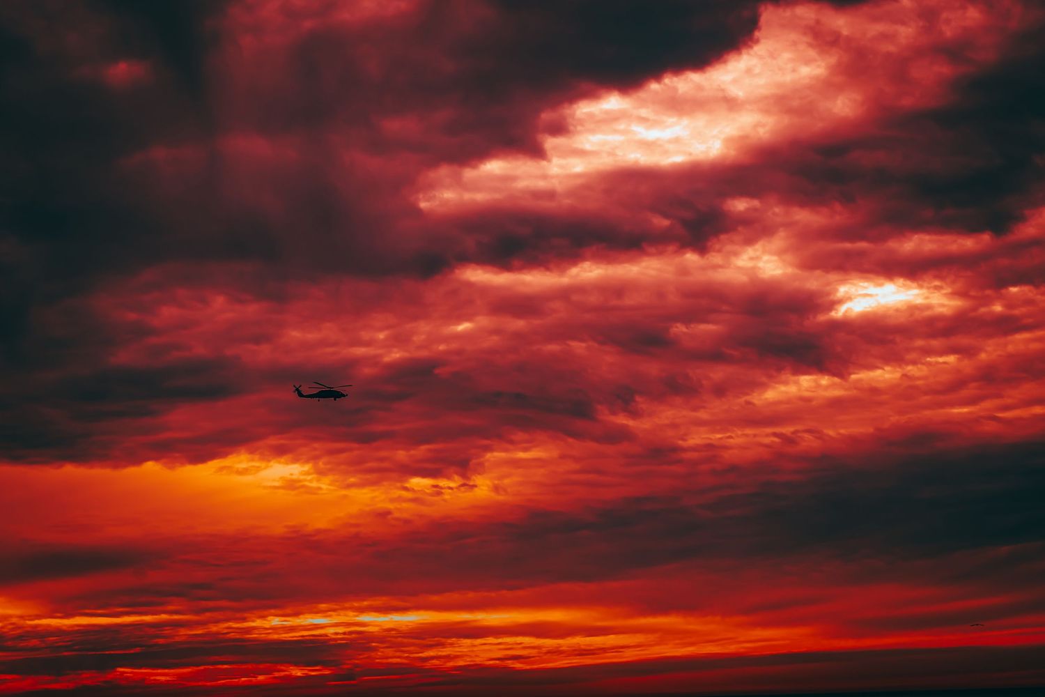 Vibrant red and orange sunset sky with dramatic cloud formations.