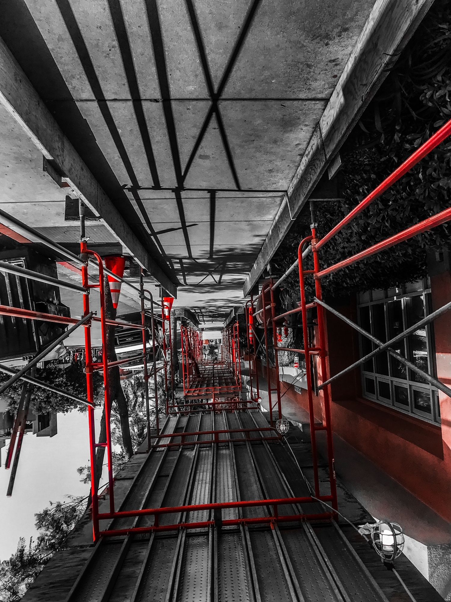 Red-accented black and white perspective shot down a scaffolding corridor.