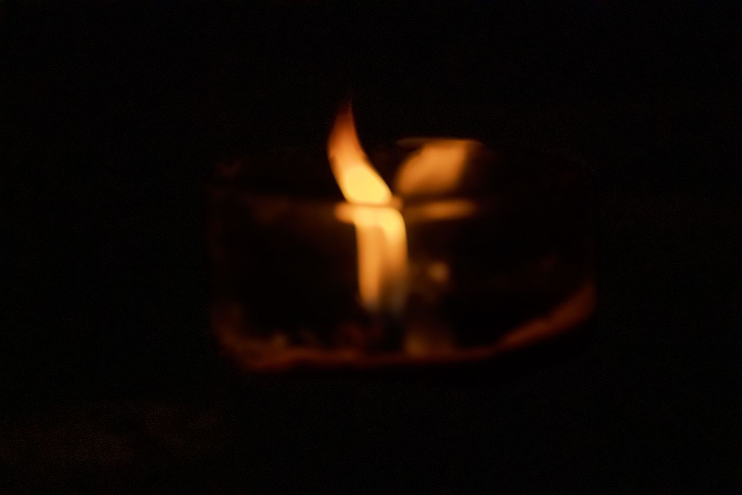 Small flickering flame dancing in darkness creating warm ambient glow.