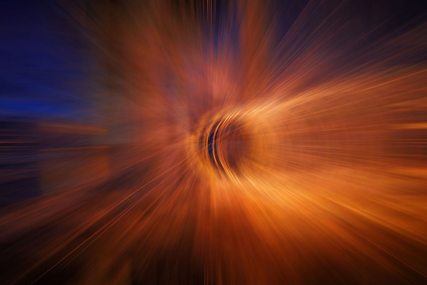 Abstract tunnel effect with orange and blue light streaks creating dynamic motion blur.