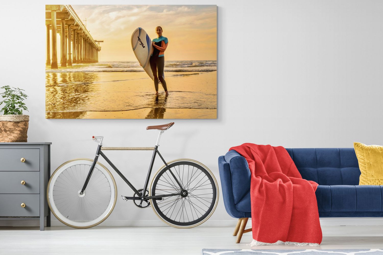 Modern living room interior with a decorative bicycle mounted on white wall next to blue couch and coral throw blanket.