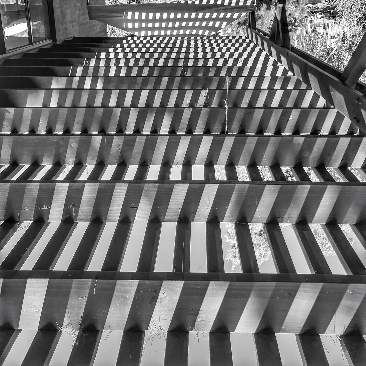 Geometric pattern of light and shadows on stairs creating striking lines and contrast.