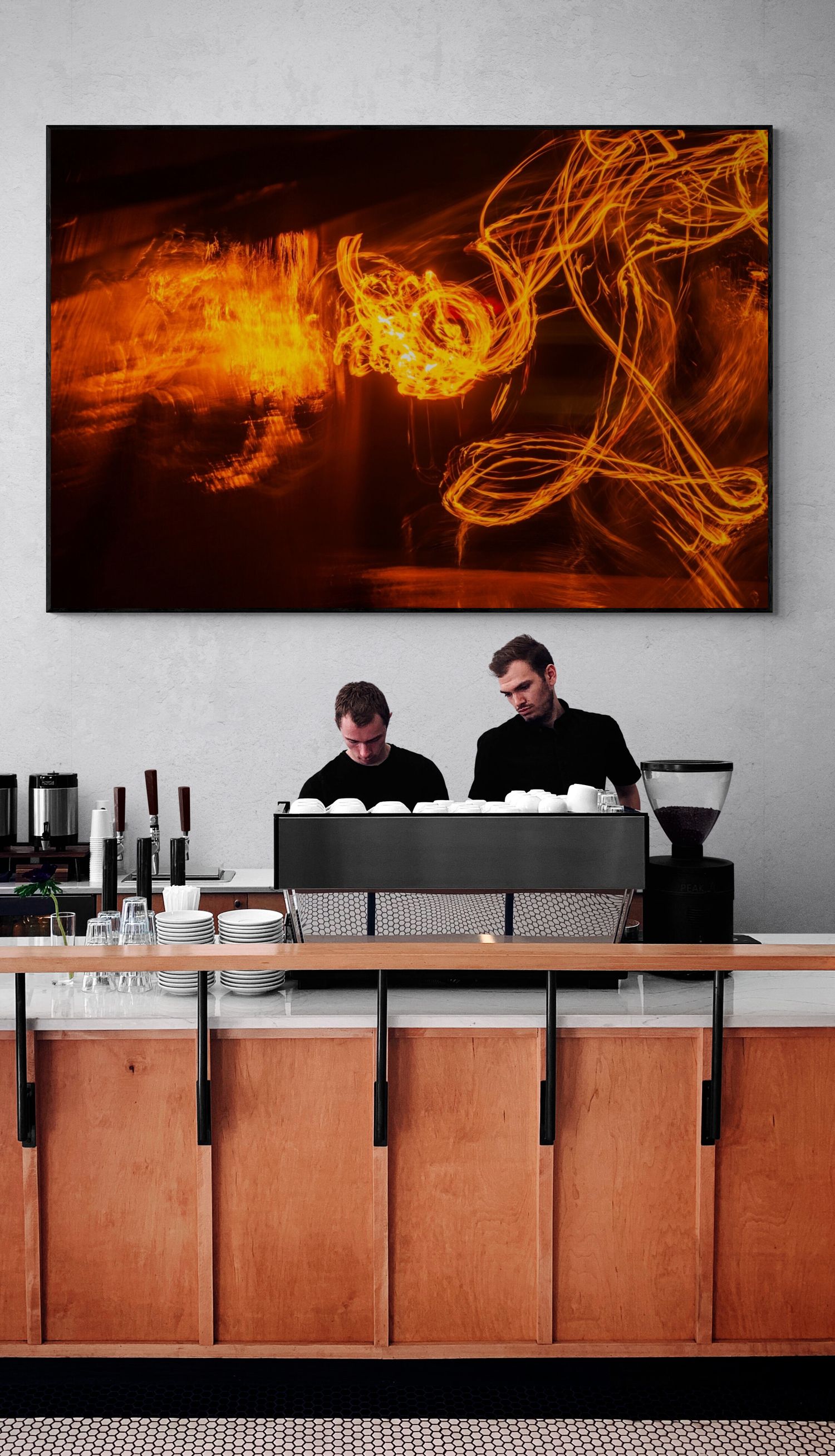 Modern coffee bar counter with orange abstract wall art and wooden cabinets.