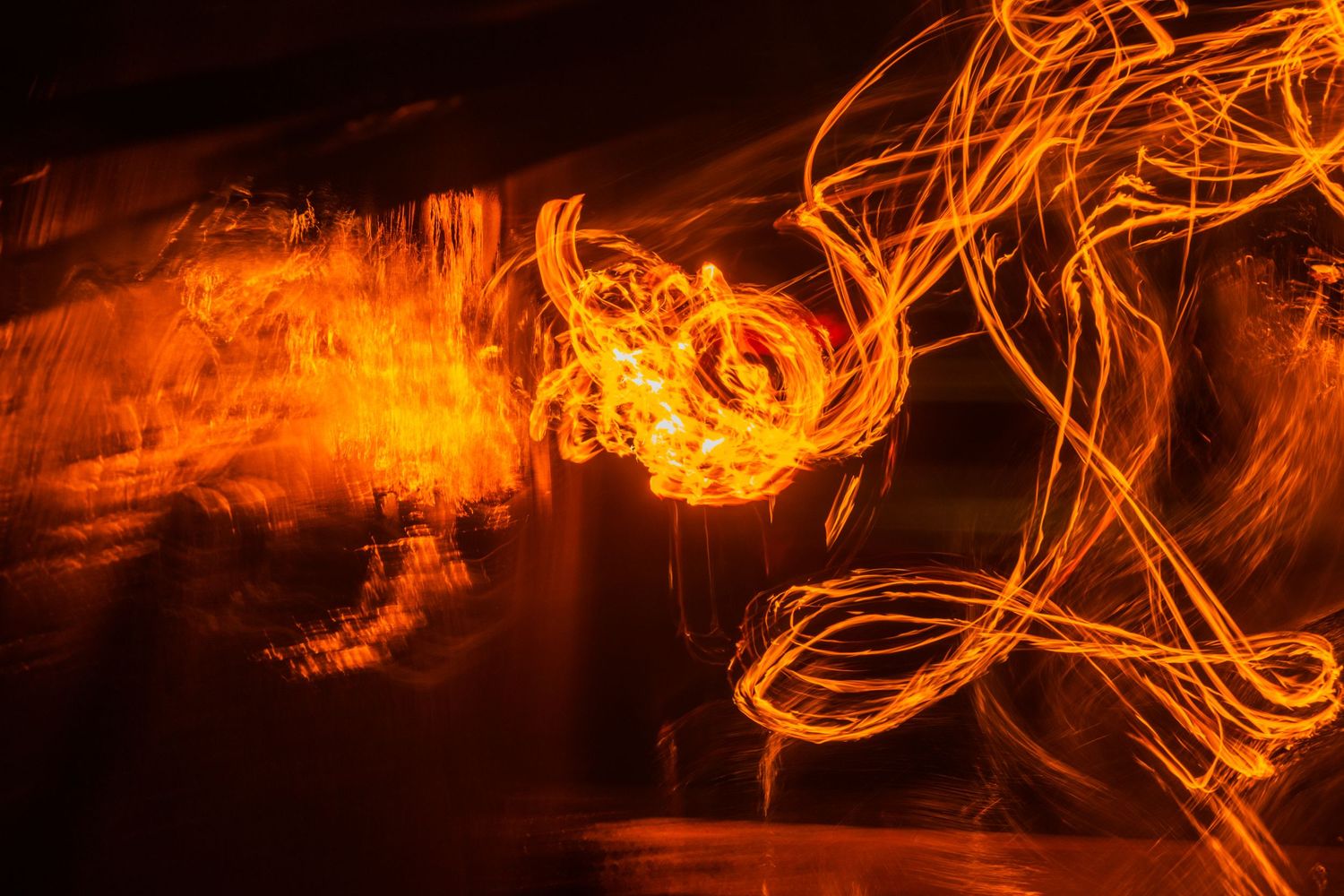 Glowing orange light trails forming ethereal patterns against a black background.