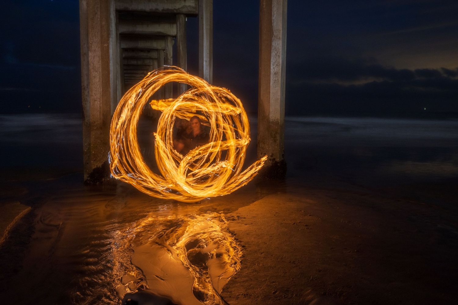 Light painting photography creating circular patterns of fire against dark nighttime setting.