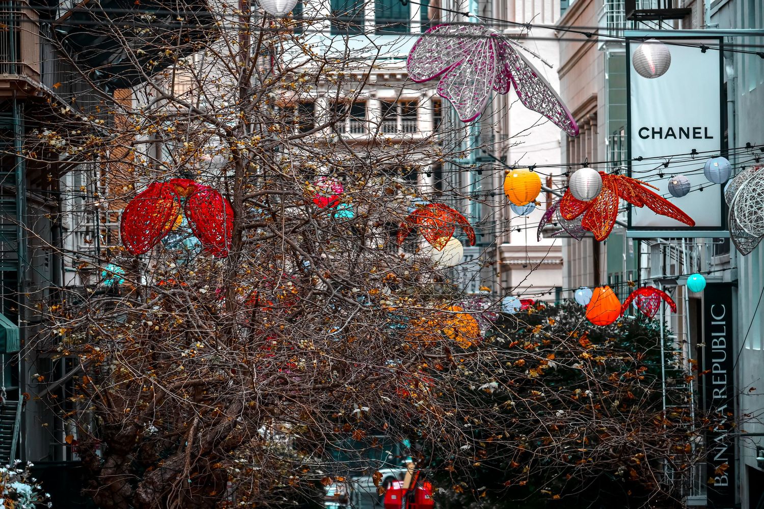 Urban street decorated with red and orange lanterns near Chanel store during festival season.