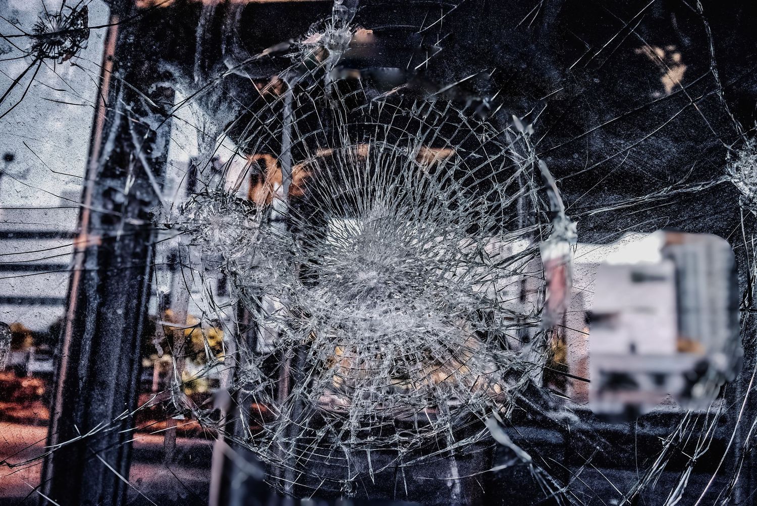 Broken glass with intricate crack patterns spreading outward from the point of impact.