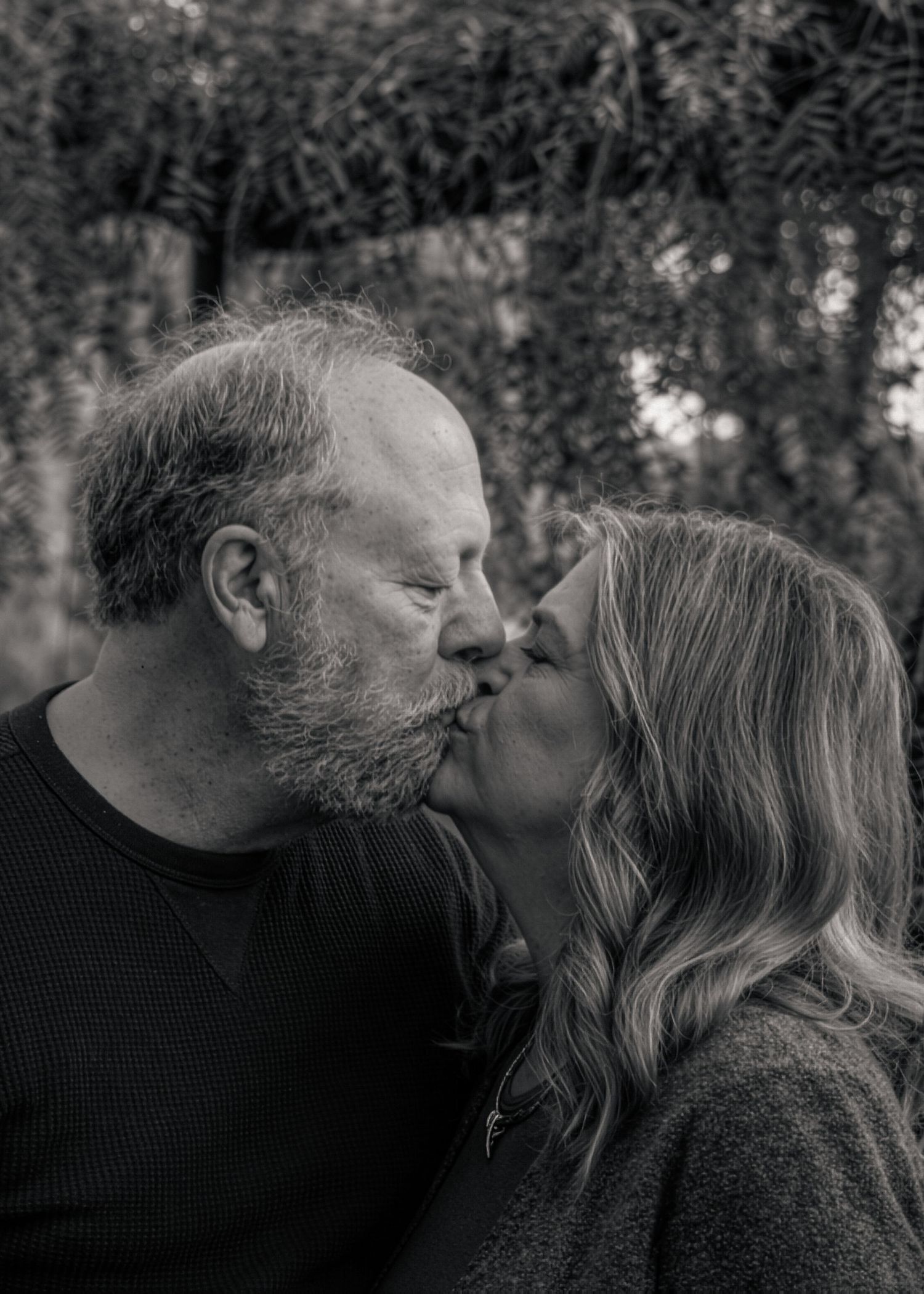 An intimate black and white portrait of two people sharing a tender moment.