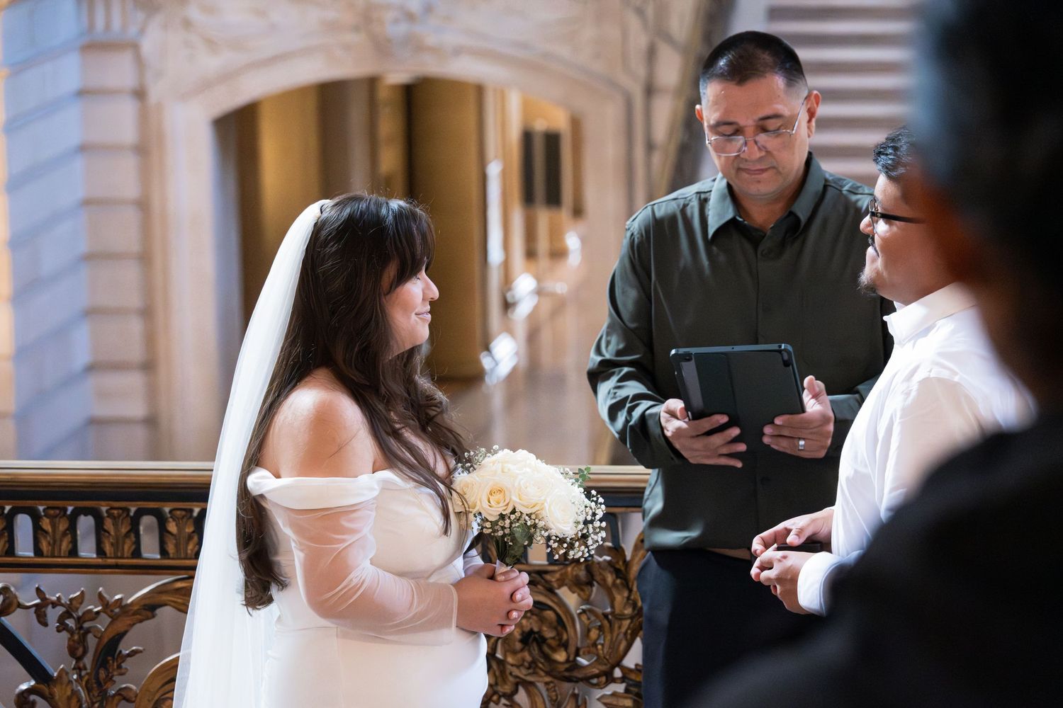 A wedding ceremony in progress at an ornate indoor venue with classical architecture.