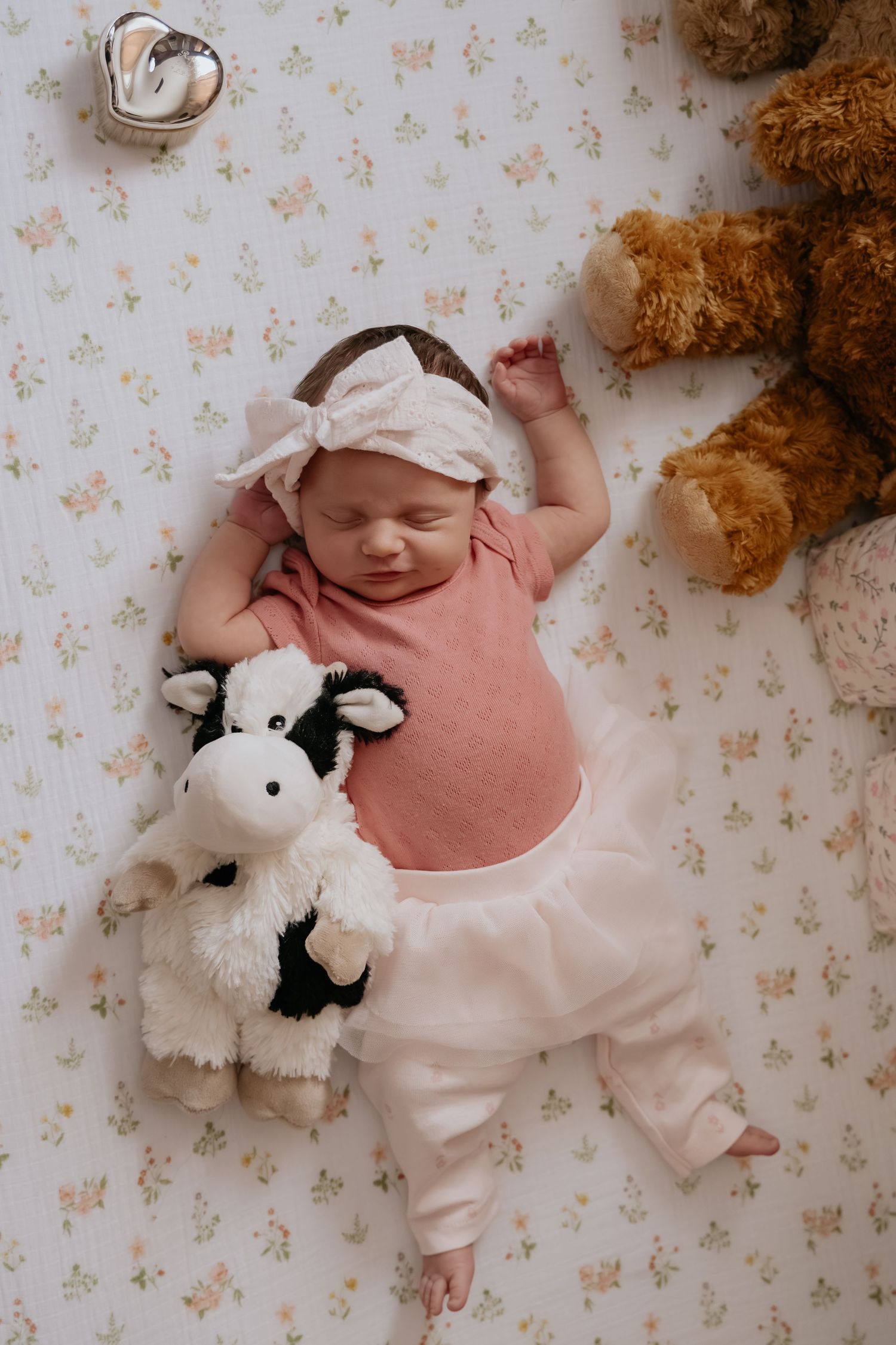 Newborn baby girl sleeping beside a plush cow and teddy bear during a lifestyle newborn photography session near Stockton, CA.