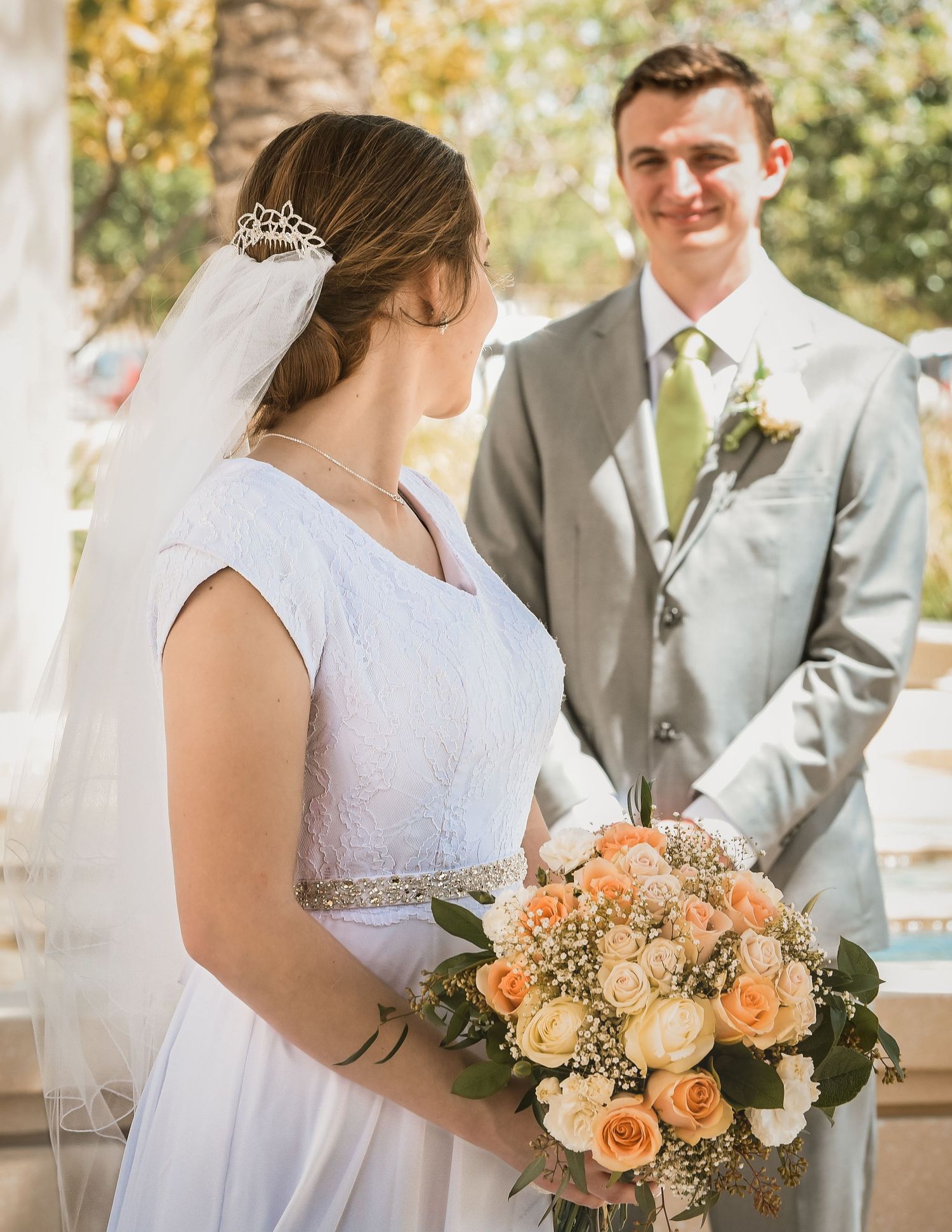 Wedding couple poses outdoors with a peach and cream floral bouquet in a series of romantic shots.