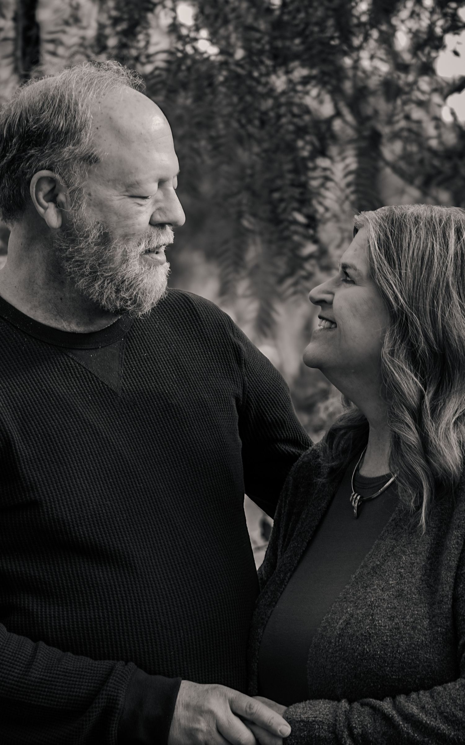 A romantic black and white photo series showing a couple sharing intimate moments and laughter together outdoors.