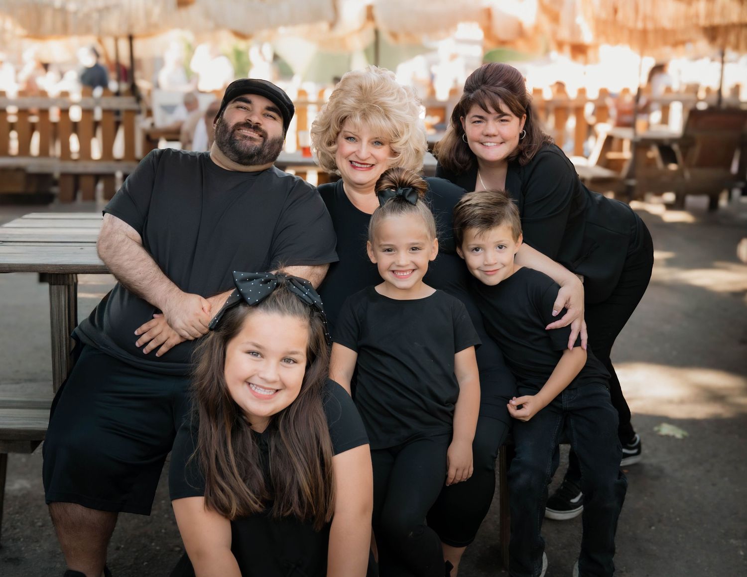 Family group photo with everyone wearing black casual clothing outdoors.