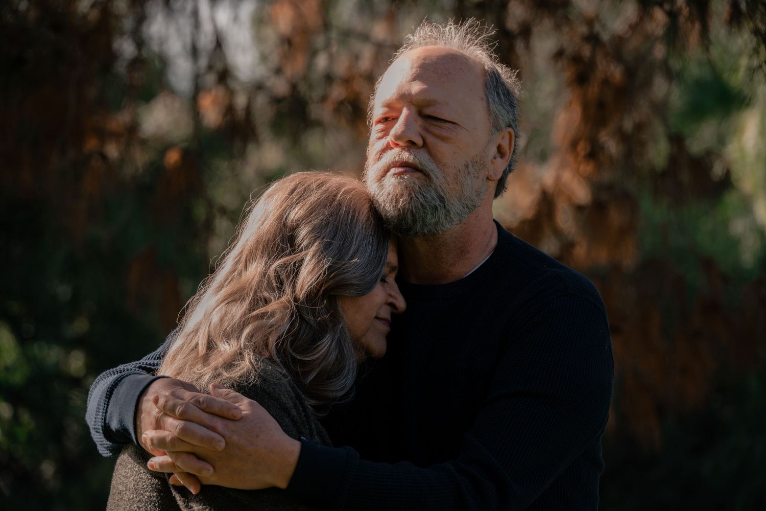 A romantic couple embraces in a warm autumn setting during a sunset photoshoot in nature. Jolie & Rae Photography, Sacramento, CA