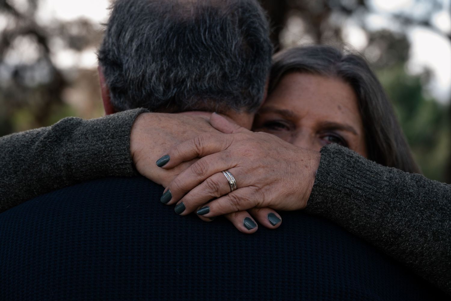 Close-up shot of two people embracing in a natural outdoor setting.